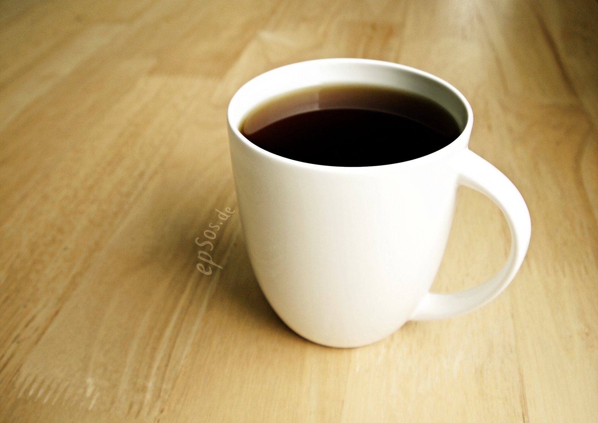 Tazza di caffè appena erogato su un piano di lavoro in legno